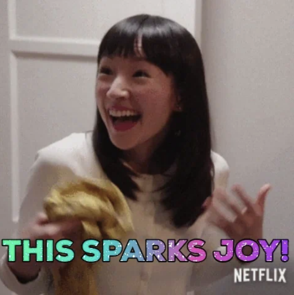 Marie Kondo holds a cloth, smiling and gesturing enthusiastically, with the text &quot;THIS SPARKS JOY!&quot;