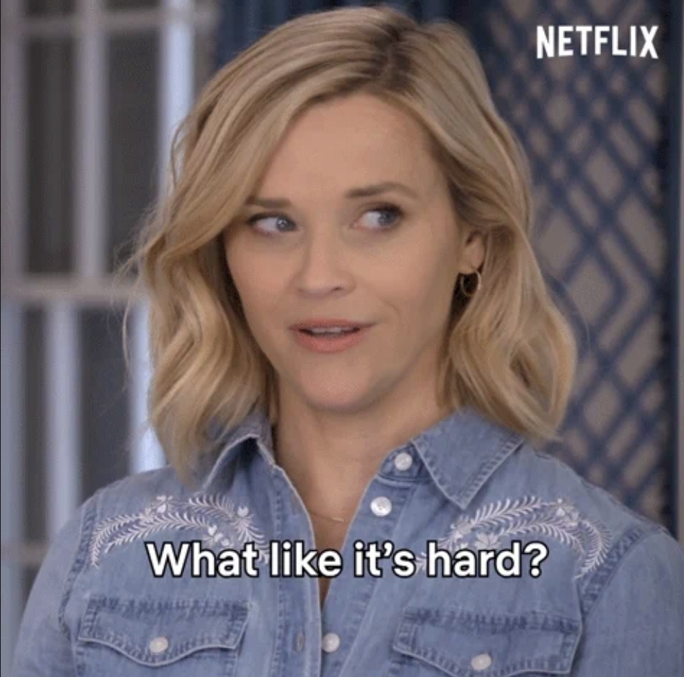 Reese Witherspoon with short blonde hair, wearing a denim shirt with embroidery. Text on image: &quot;What like it&#x27;s hard?&quot;