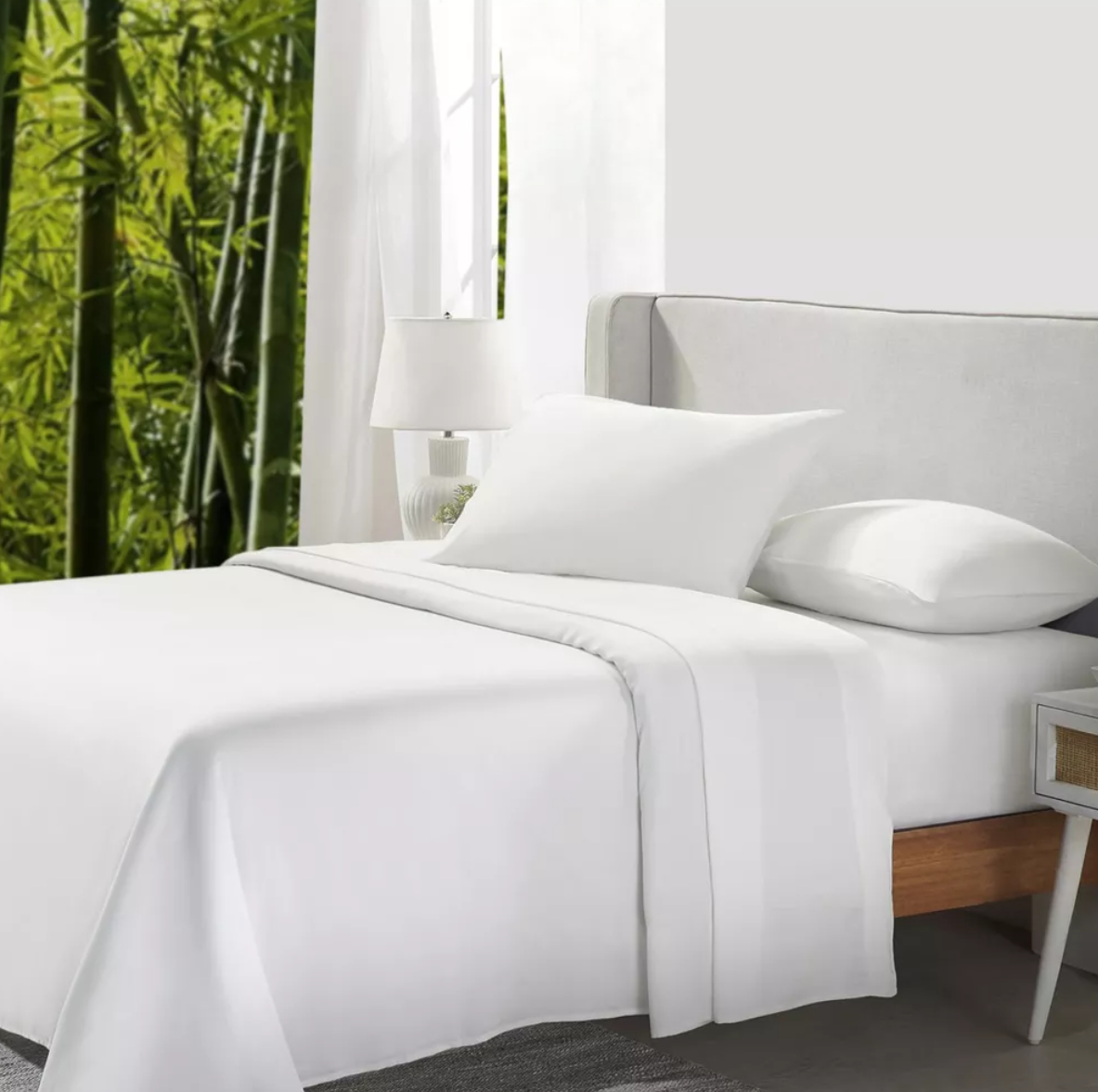 the white sheets in a modern bedroom, featuring a large window showing bamboo plants outside