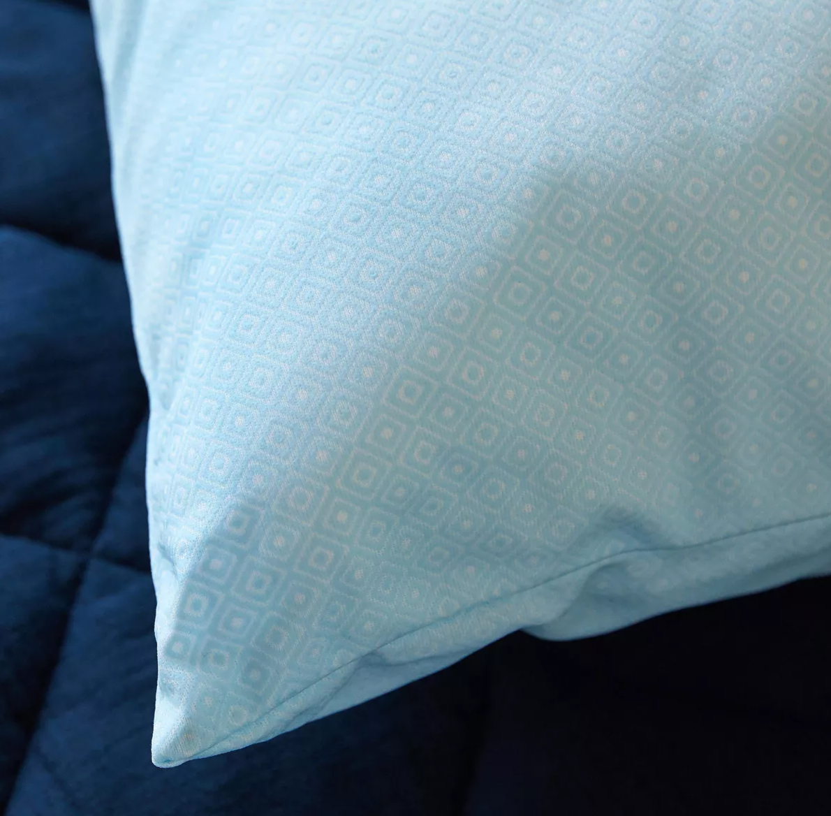 A close-up image of the pillow resting on a dark quilted surface