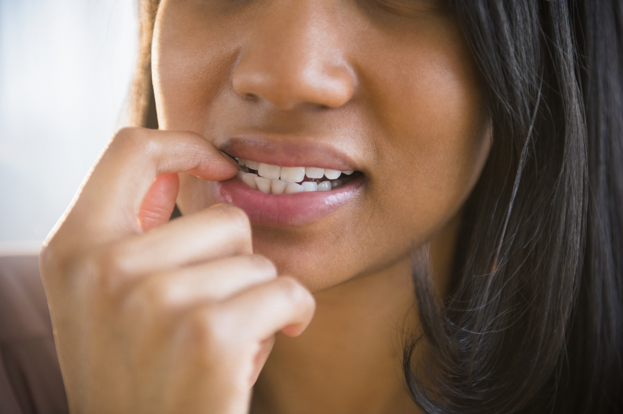 Close-up of a person biting their nails, partially covering their mouth with a hand, suggesting anxiety or nervousness