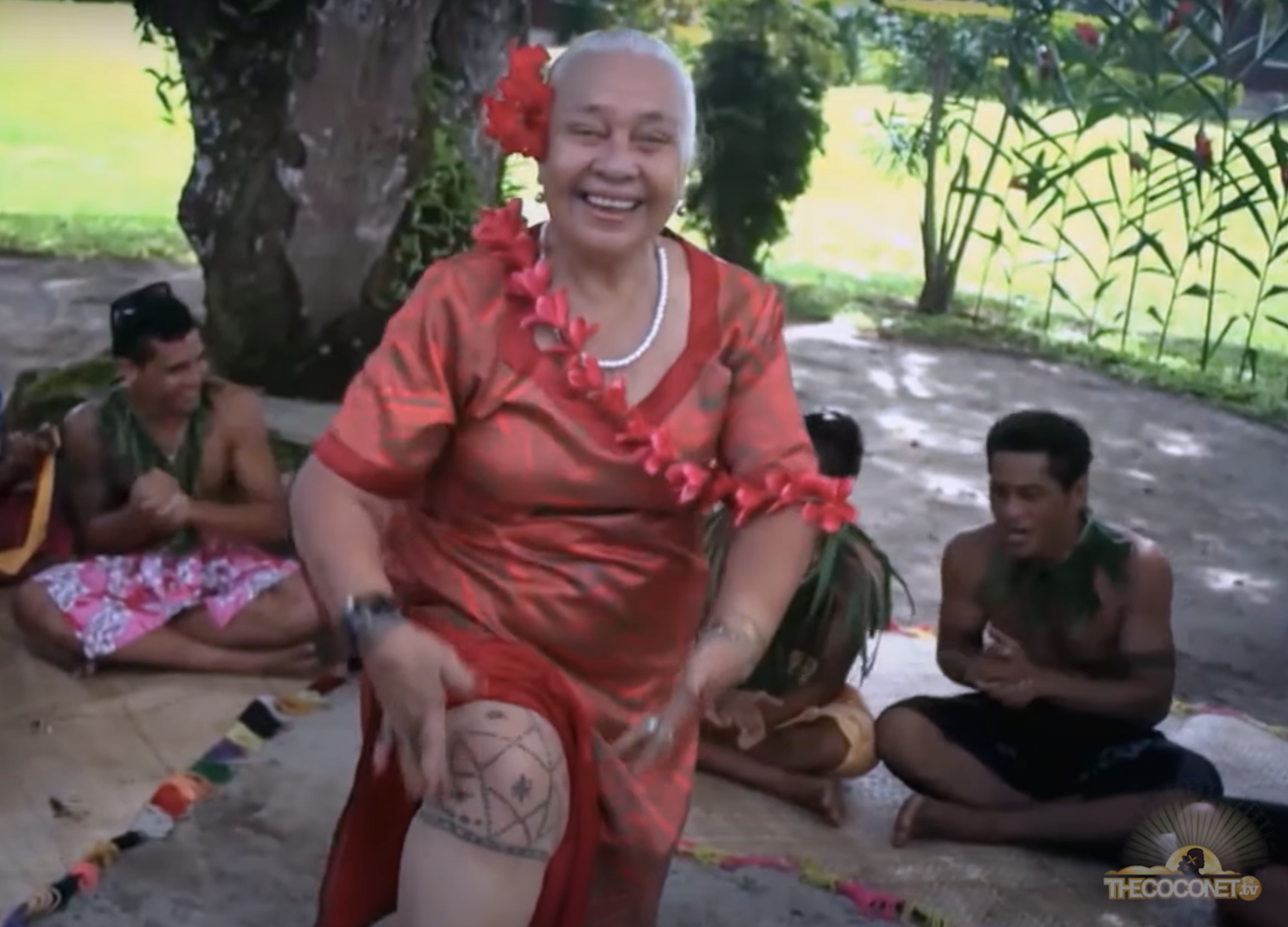 Woman in red performs traditional dance with others in background