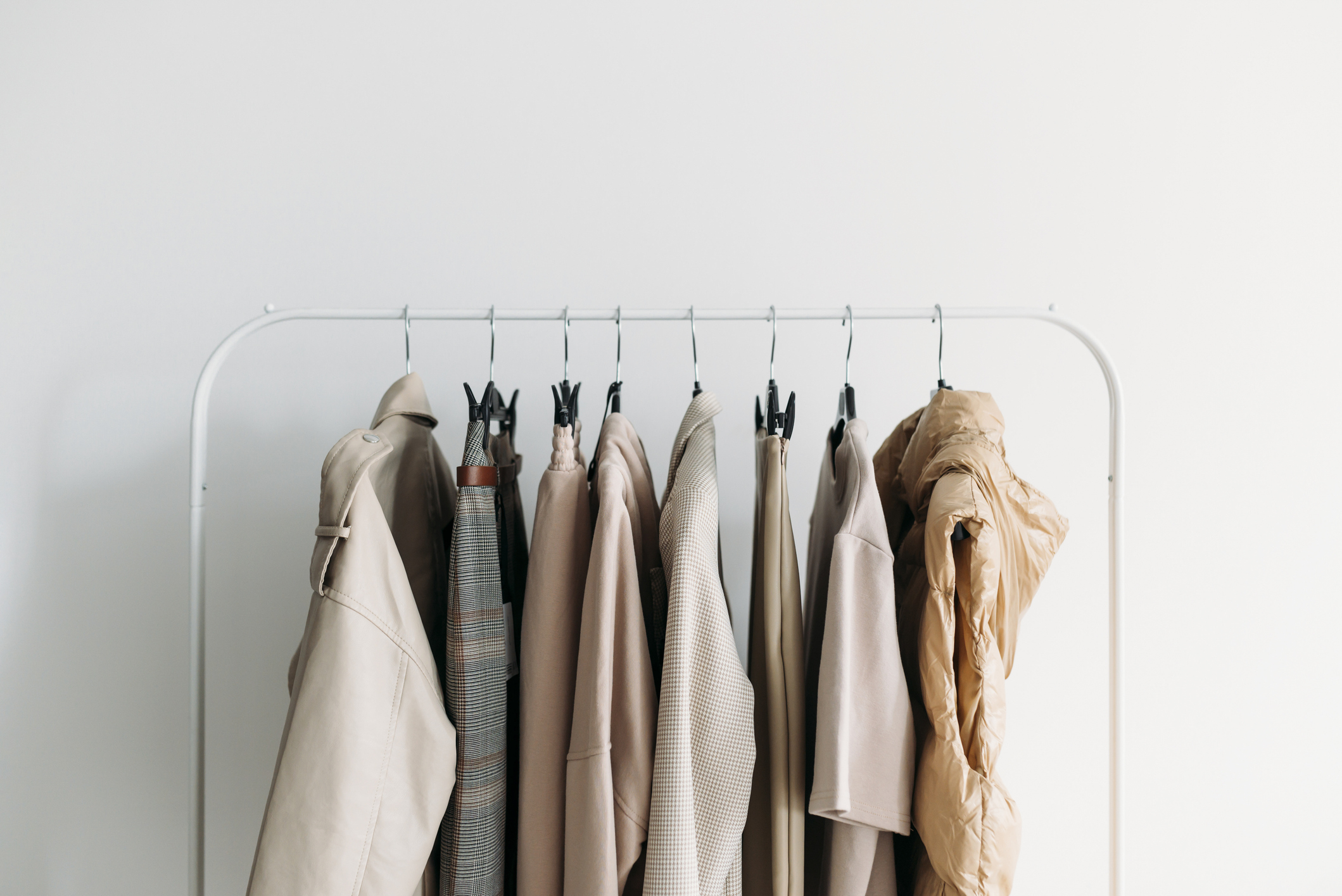 A clothing rack with various neutral-toned jackets and coats neatly hung