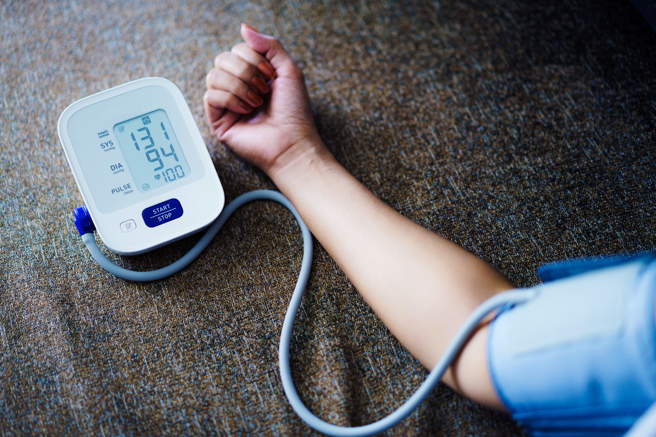 Close-up of a person&#x27;s arm with a blood pressure cuff, displaying the reading of 131/94 mmHg and a pulse rate of 100 on the monitor