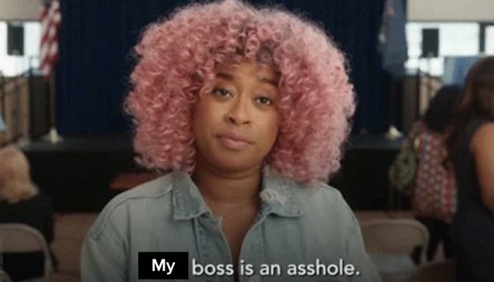 A woman with curly hair and a denim jacket stares straight ahead with a neutral expression. Text on the image reads, &quot;Your boss is an asshole.&quot;