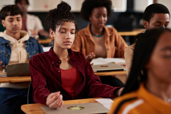 Students sitting in a classroom, with one student in the foreground meditating