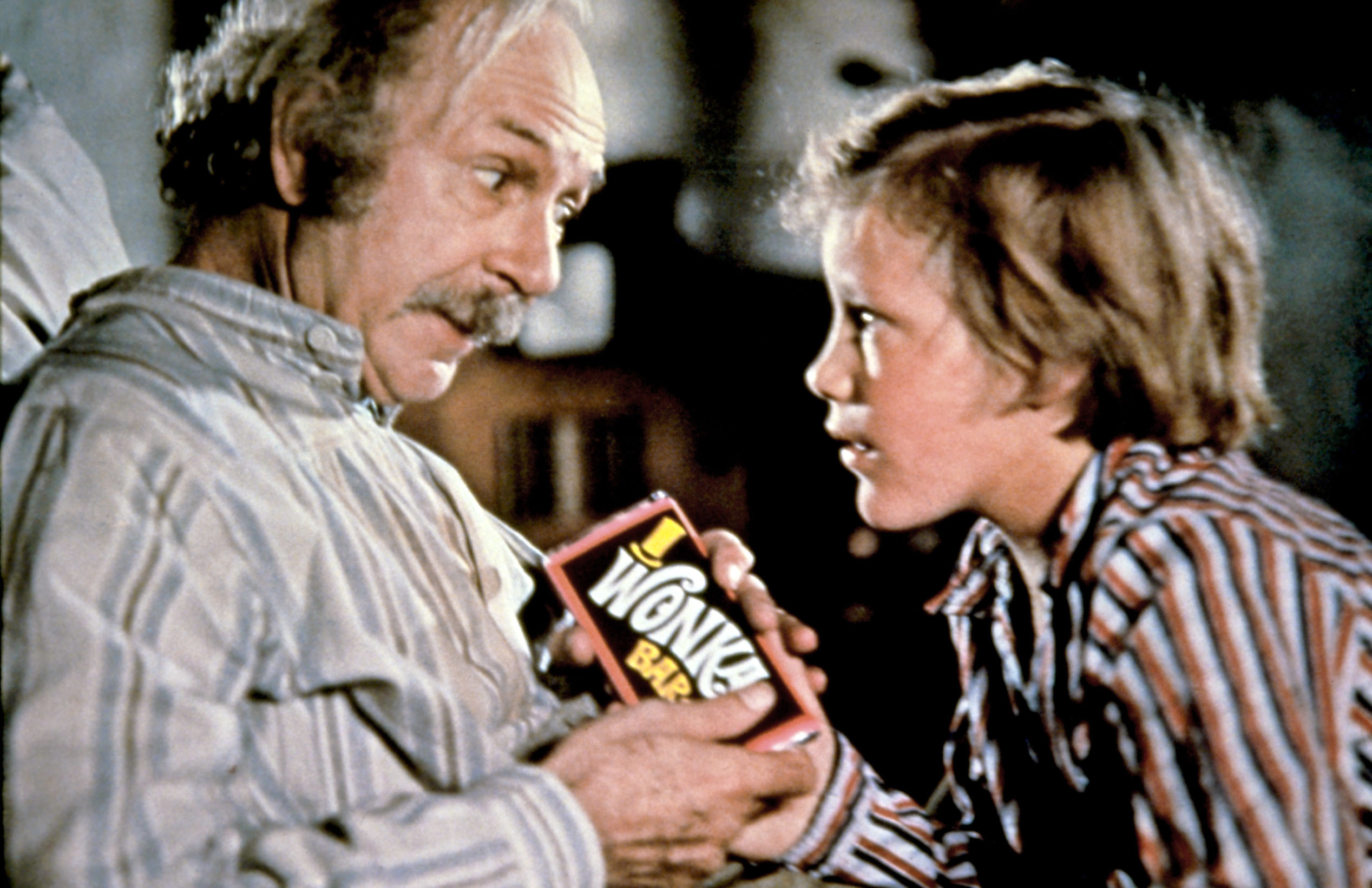Jack Albertson and Peter Ostrum, dressed in pajamas, holding a Wonka Bar in a scene from &quot;Willy Wonka &amp;amp; the Chocolate Factory.&quot;