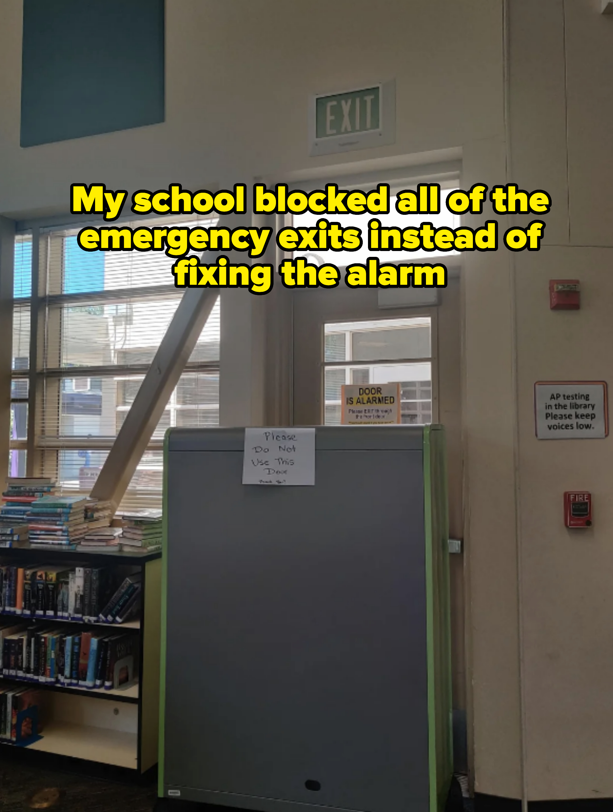 Library door with a sign warning &quot;Please Do Not Use This Door&quot; and another cautioning &quot;DOOR IS ALARMED.&quot; Bookshelves and an exit sign are visible