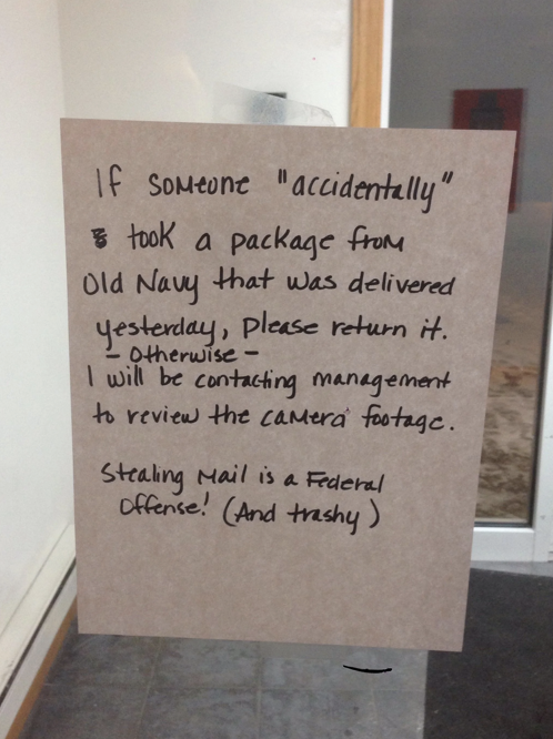 A handwritten note on a door requests the return of a package from Old Navy, warning of contacting management for camera footage and labeling mail theft as a federal offense