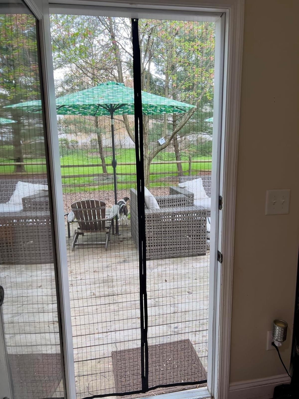 Screened patio door with outdoor furniture and an umbrella visible through the screen