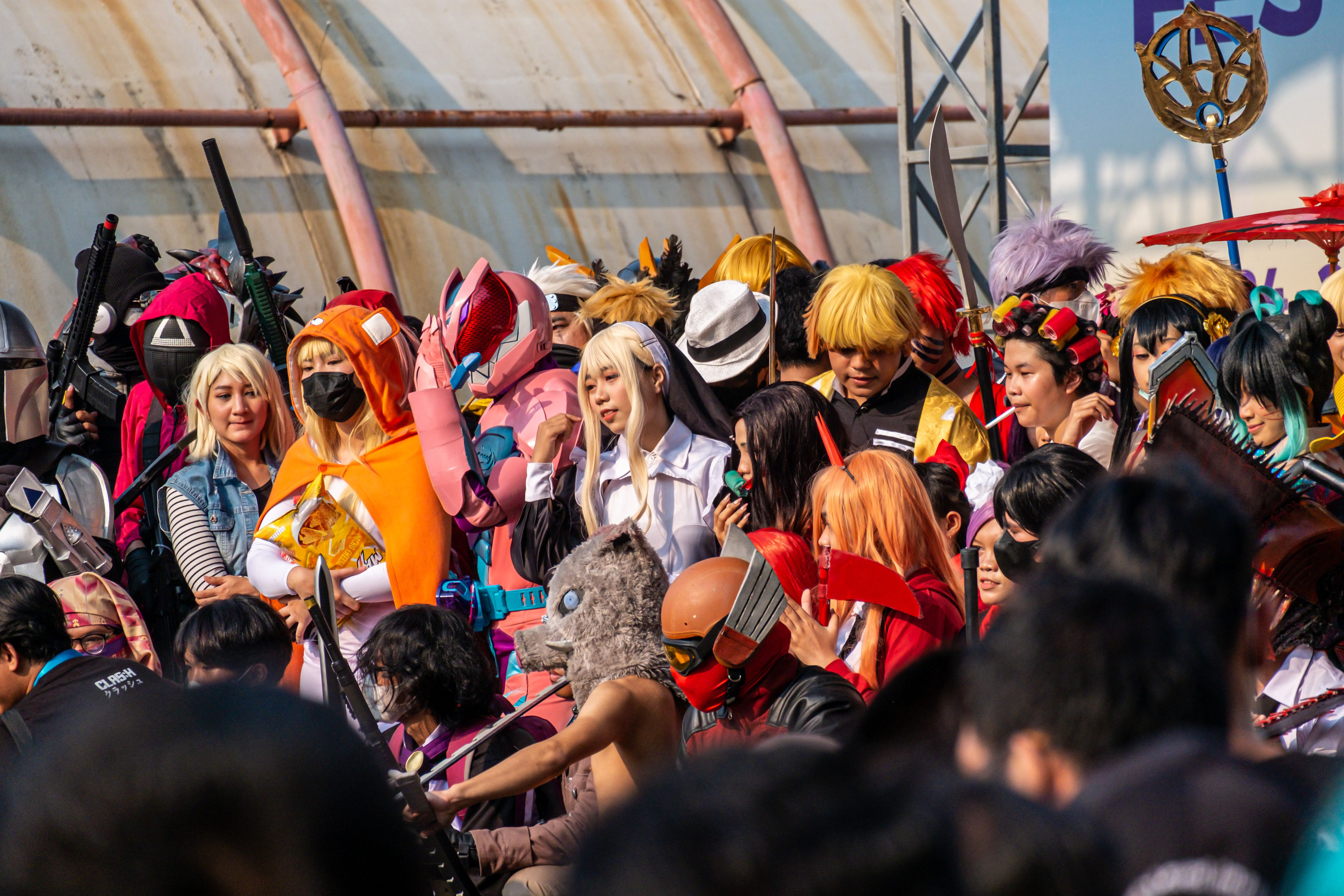 A large group of people in various detailed cosplay costumes at a convention. Some characters include anime, video game, and fantasy figures