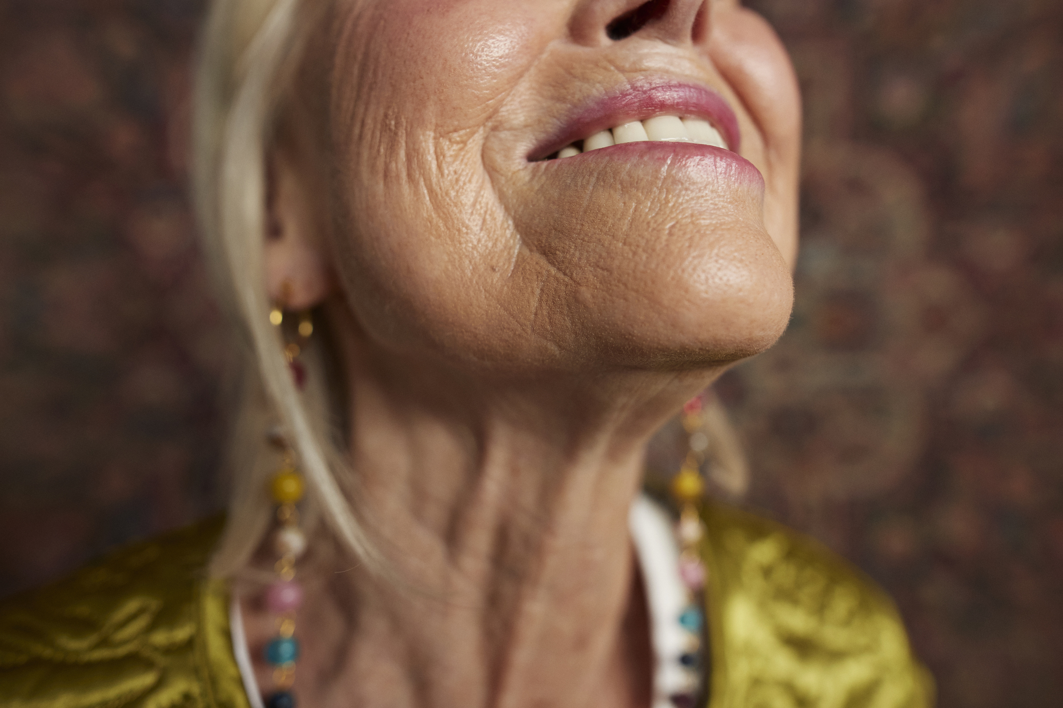 Close-up of an elderly person&#x27;s smiling face, showing earrings with colorful beads