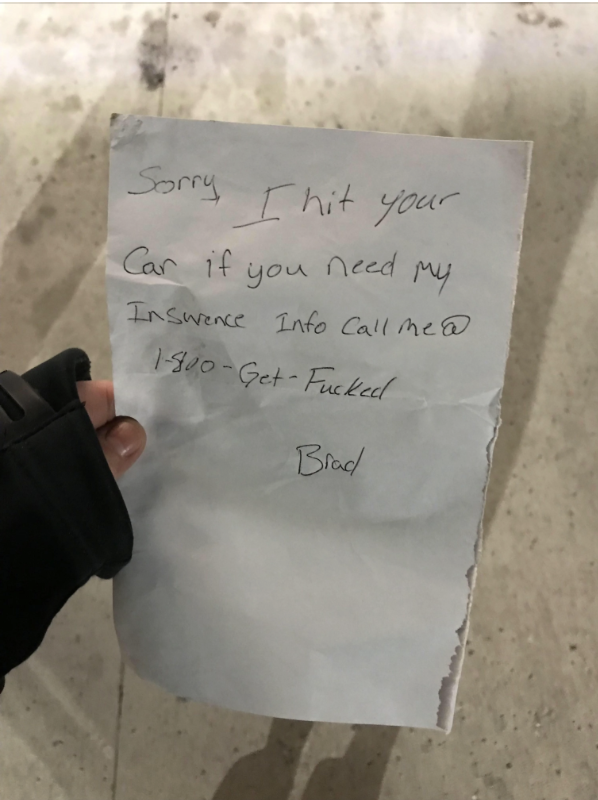 A person&#x27;s hand holds a note that reads, &quot;Sorry, I hit your car if you need my insurance info call me @ 1-800-Get-Fucked - Brad.&quot;