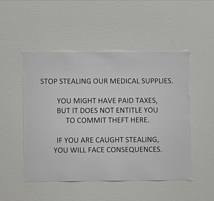 Sign on a wall reading: &quot;STOP STEALING OUR MEDICAL SUPPLIES. YOU MIGHT HAVE PAID TAXES, BUT IT DOES NOT ENTITLE YOU TO COMMIT THEFT HERE. IF YOU ARE CAUGHT STEALING, YOU WILL FACE CONSEQUENCES.&quot;