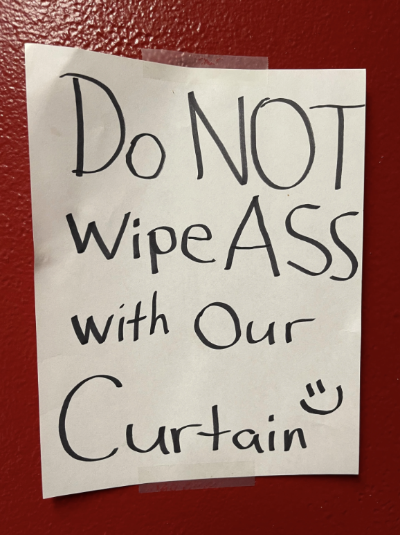 A hand-written sign taped to a wall reads, &quot;Do NOT wipe ass with our curtain :)&quot;