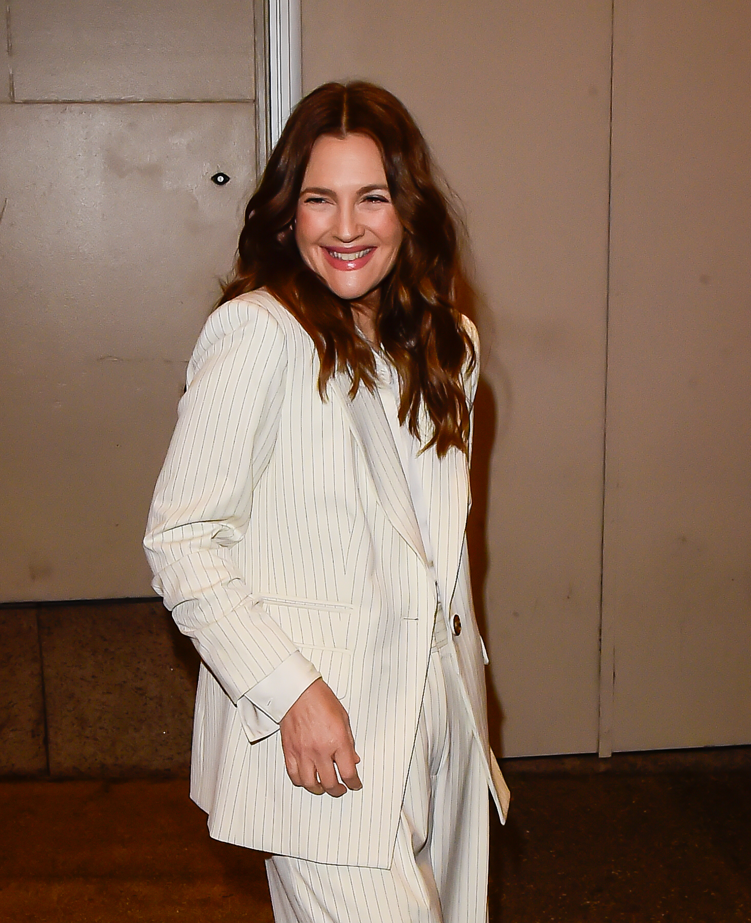 Drew Barrymore smiling and posing in a pinstriped suit