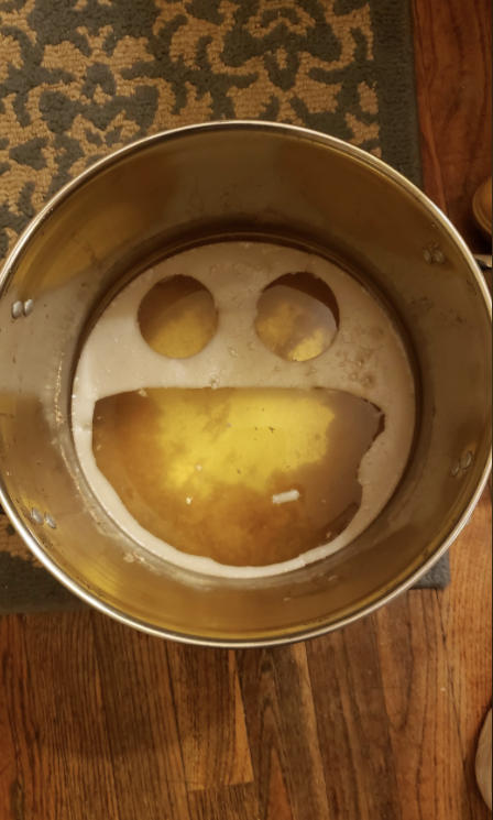 A large pot with liquid inside shows a smiling face pattern formed by foam or residue floating on top