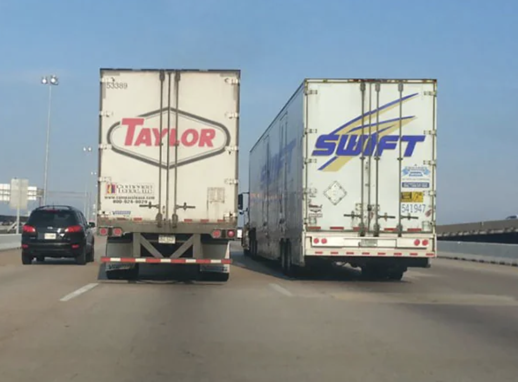 Two trucks labeled &quot;Taylor&quot; and &quot;Swift&quot; are side by side on a highway, creating an amusing visual pun referencing the singer Taylor Swift