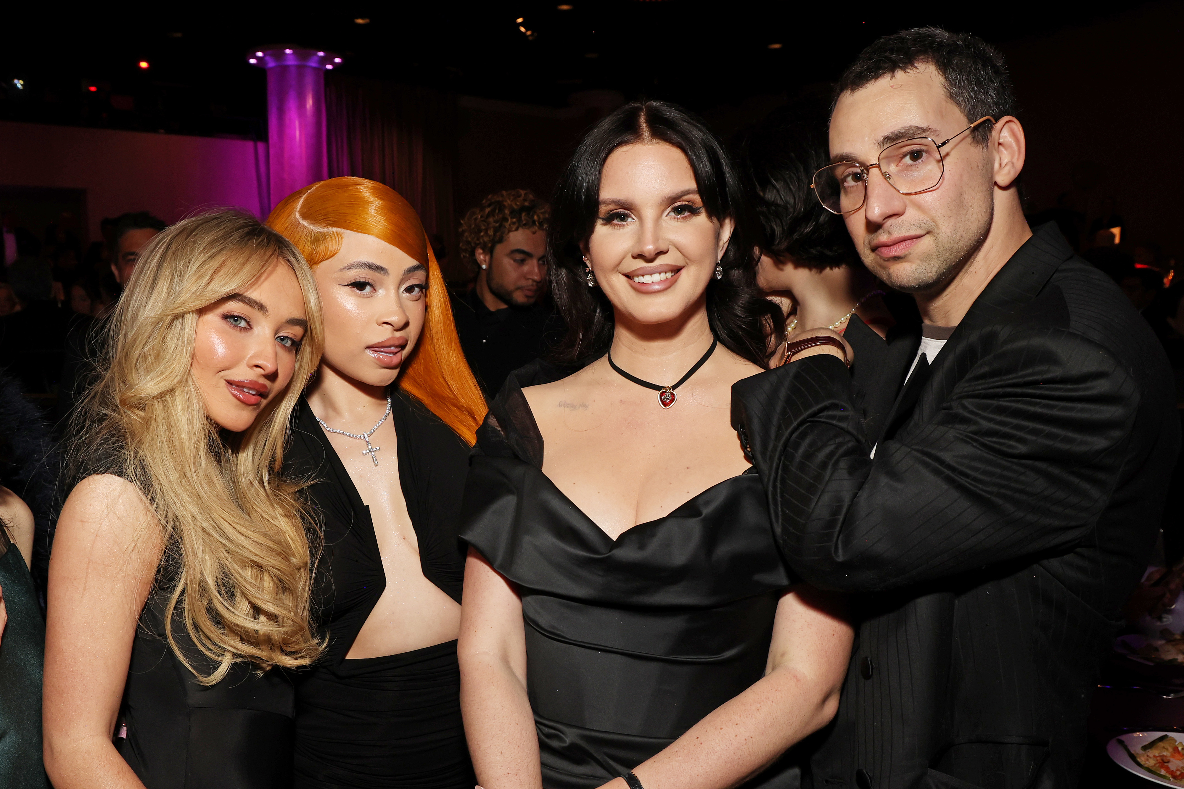 Sabrina Carpenter, Ice Spice, Lana Del Rey, and Jack Antonoff stand together at an event. All are wearing formal black attire and smiling at the camera