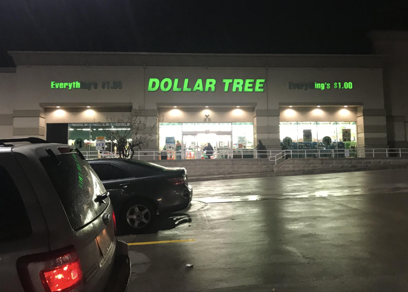 A Dollar Tree store at night with cars parked outside. The store&#x27;s sign says &quot;Everything&#x27;s $1.00&quot;