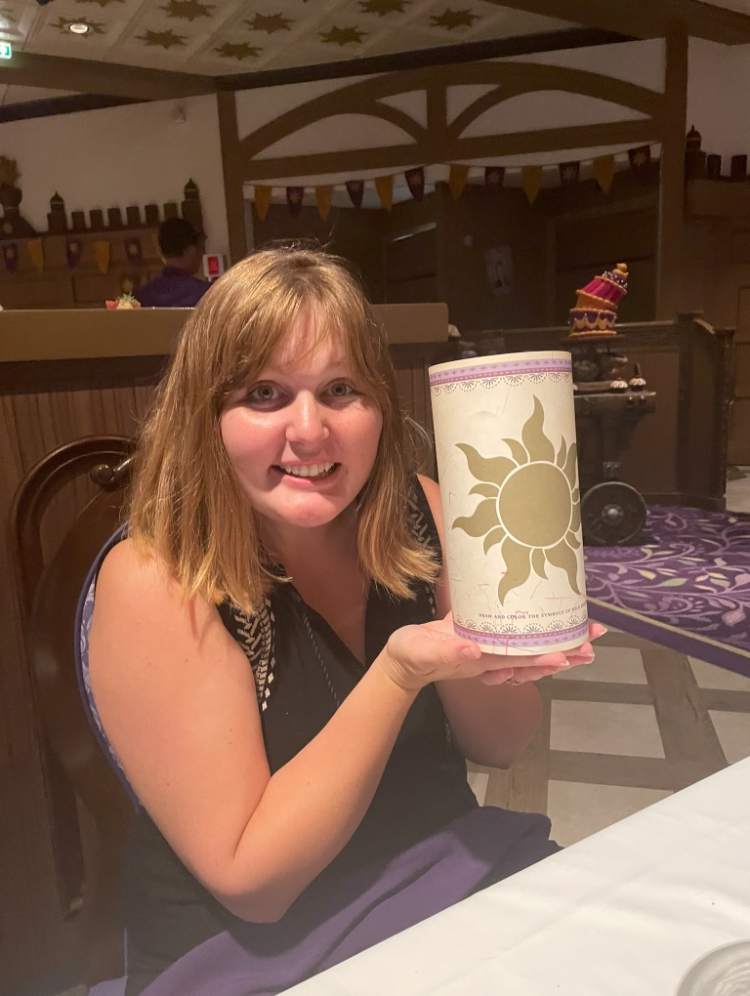 A woman smiling and holding a container with a sun design at a restaurant