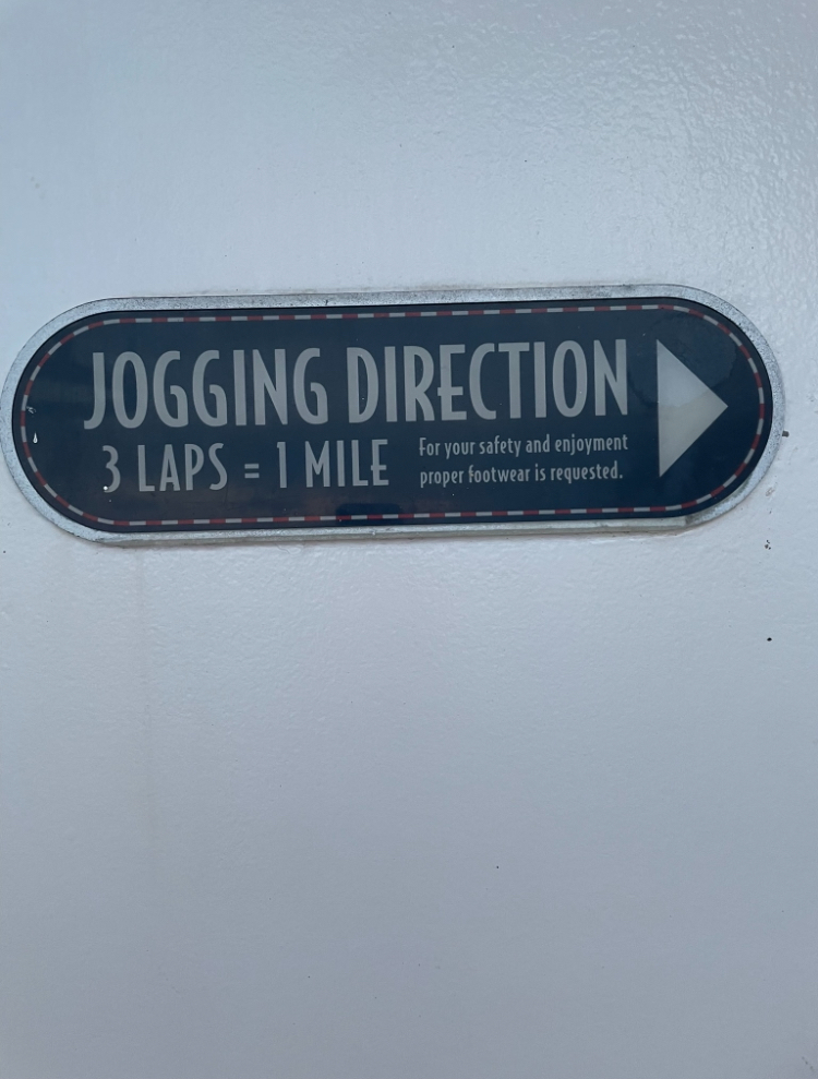 Sign indicating jogging direction with the message: &quot;3 laps = 1 mile. For your safety and enjoyment, proper footwear is requested.&quot;
