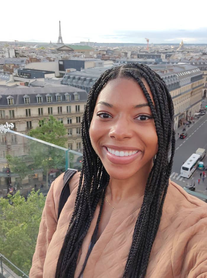 Woman smiles with Paris cityscape, including the Eiffel Tower, in the background