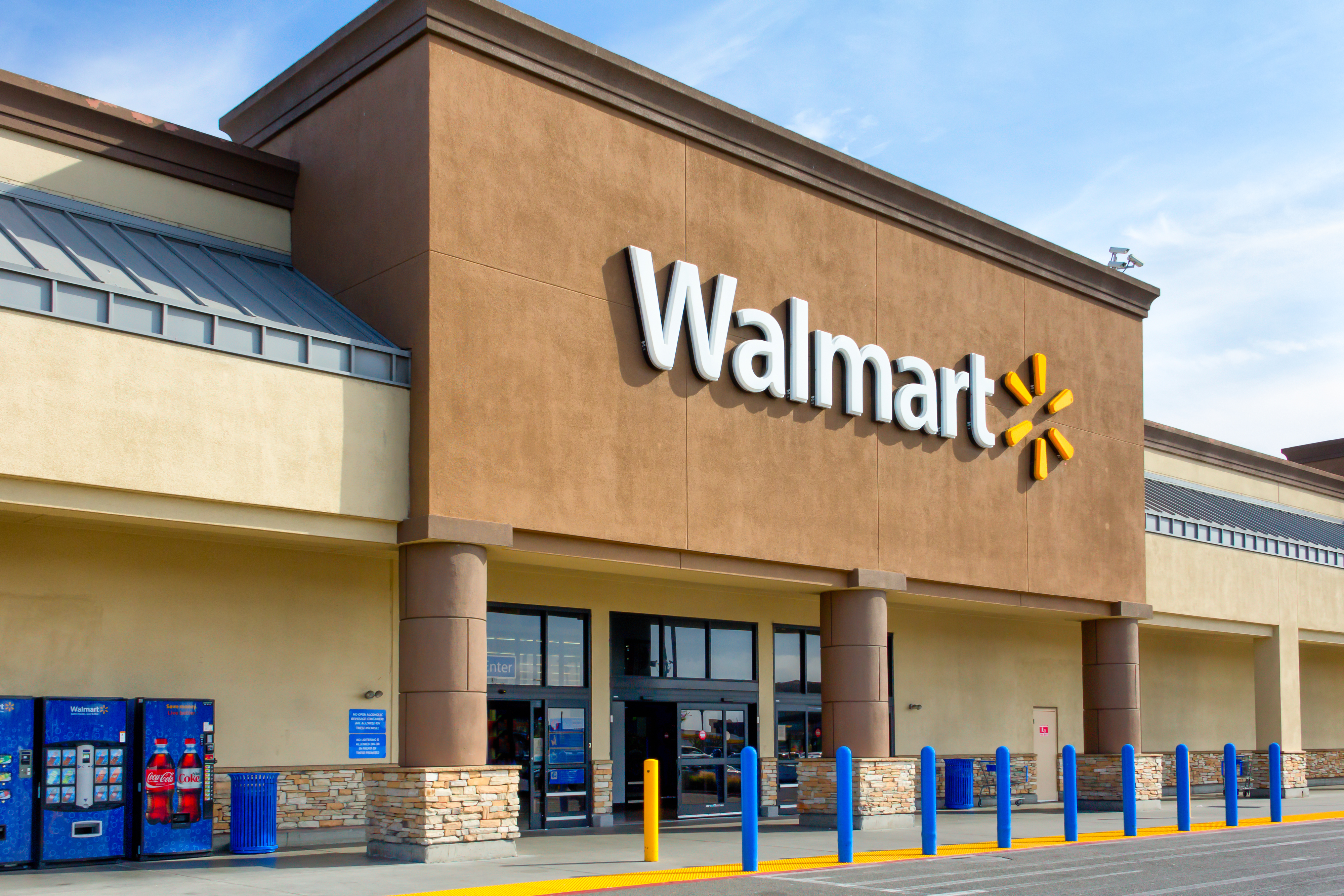 Front entrance of a Walmart store with vending machines and shopping carts visible outside