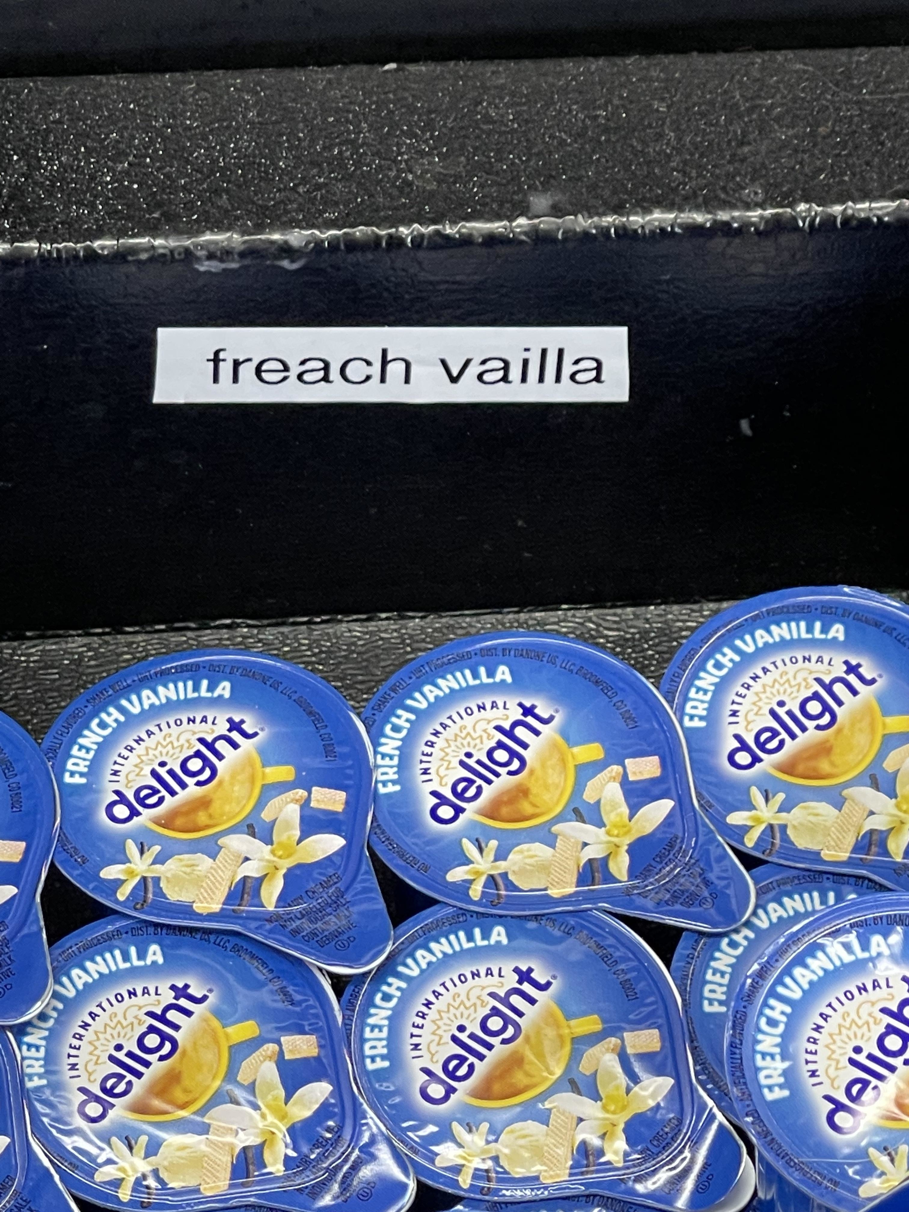 Image of coffee creamer cups labeled &quot;French Vanilla,&quot; with a sign mistakenly spelling it as &quot;freach vailla.&quot;