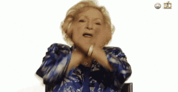 Betty White clapping and smiling enthusiastically in front of a white background