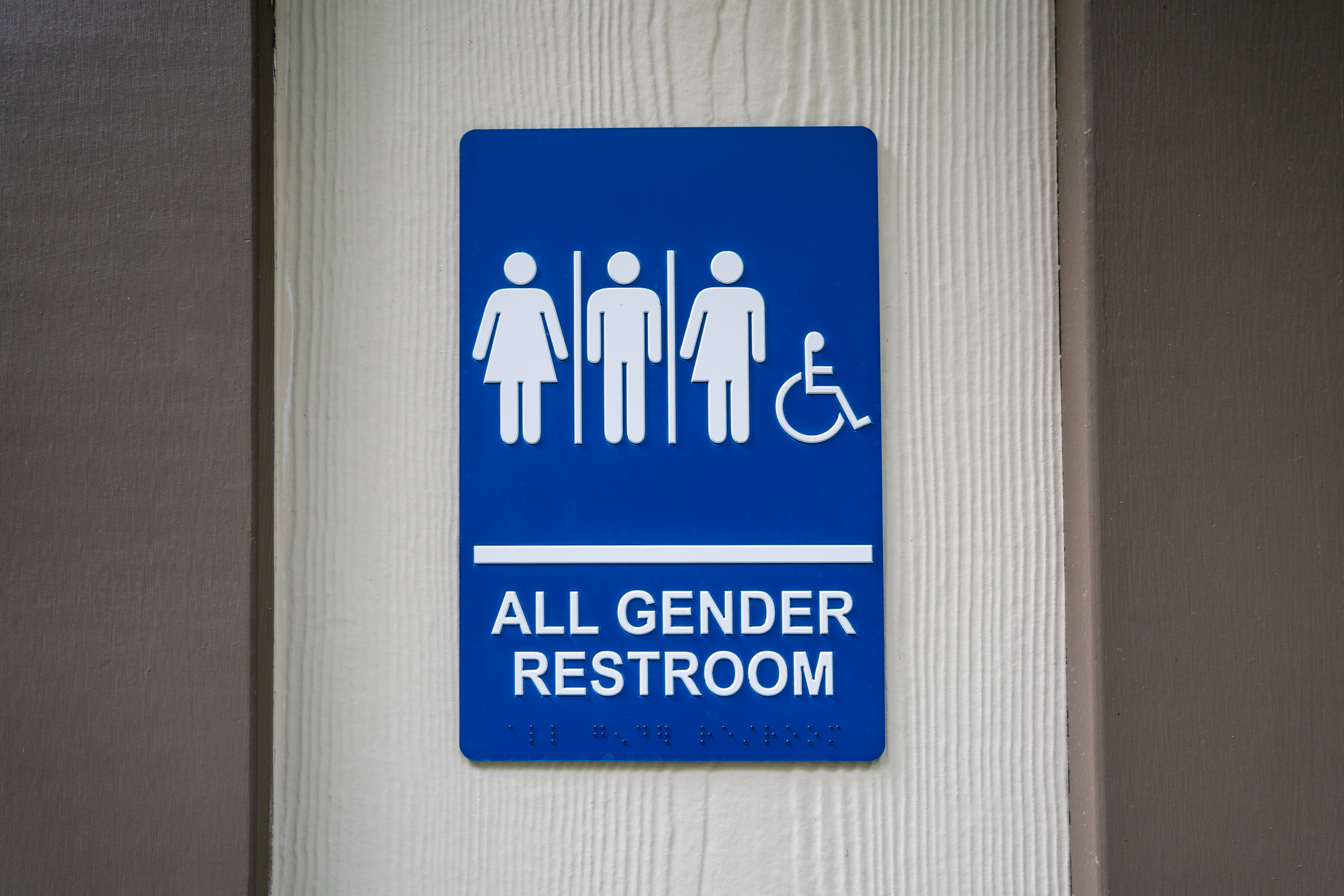 Sign on a wall reads &quot;All Gender Restroom&quot; with symbols for male, female, non-binary, and wheelchair accessible