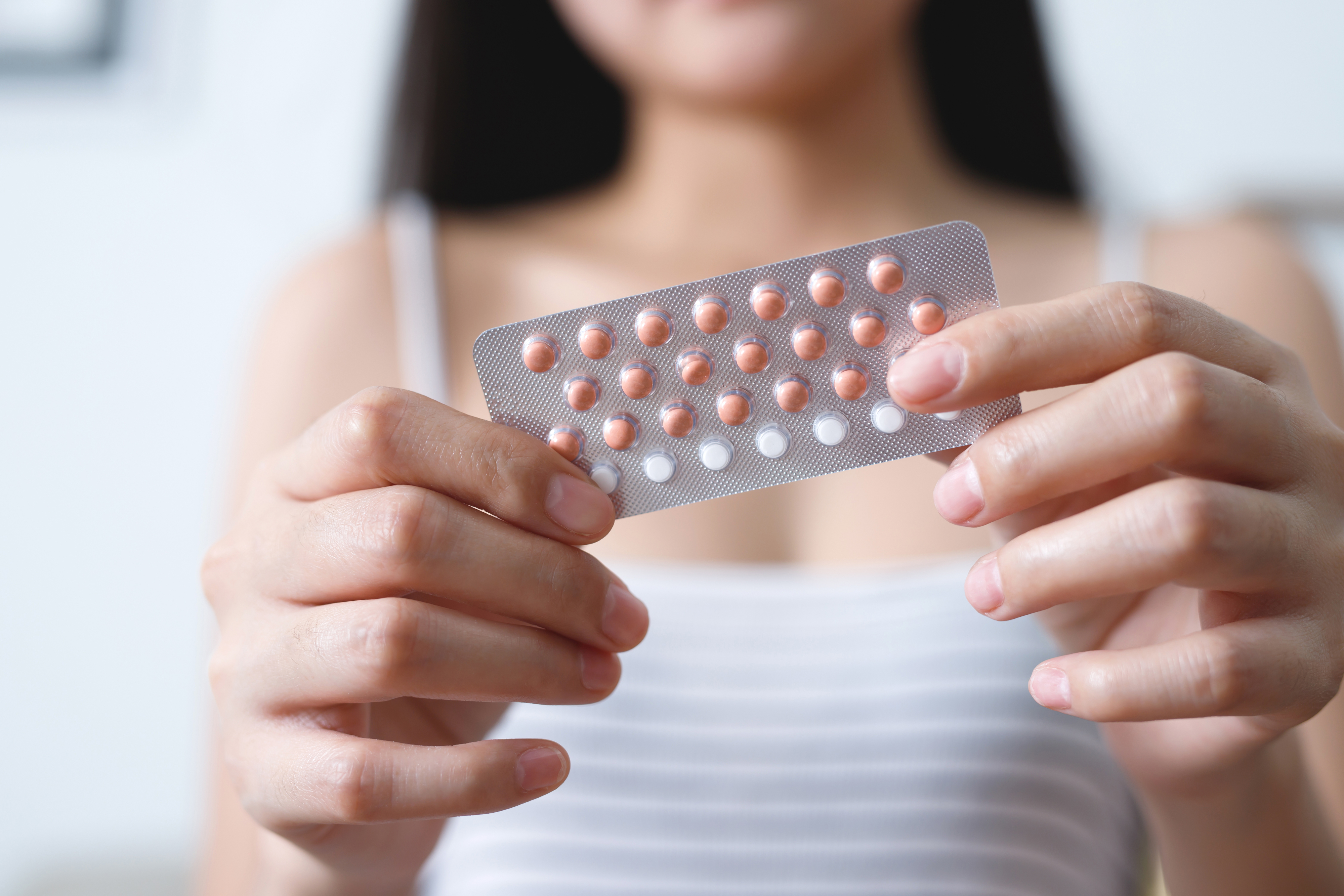 A person holds a pack of birth control pills in both hands