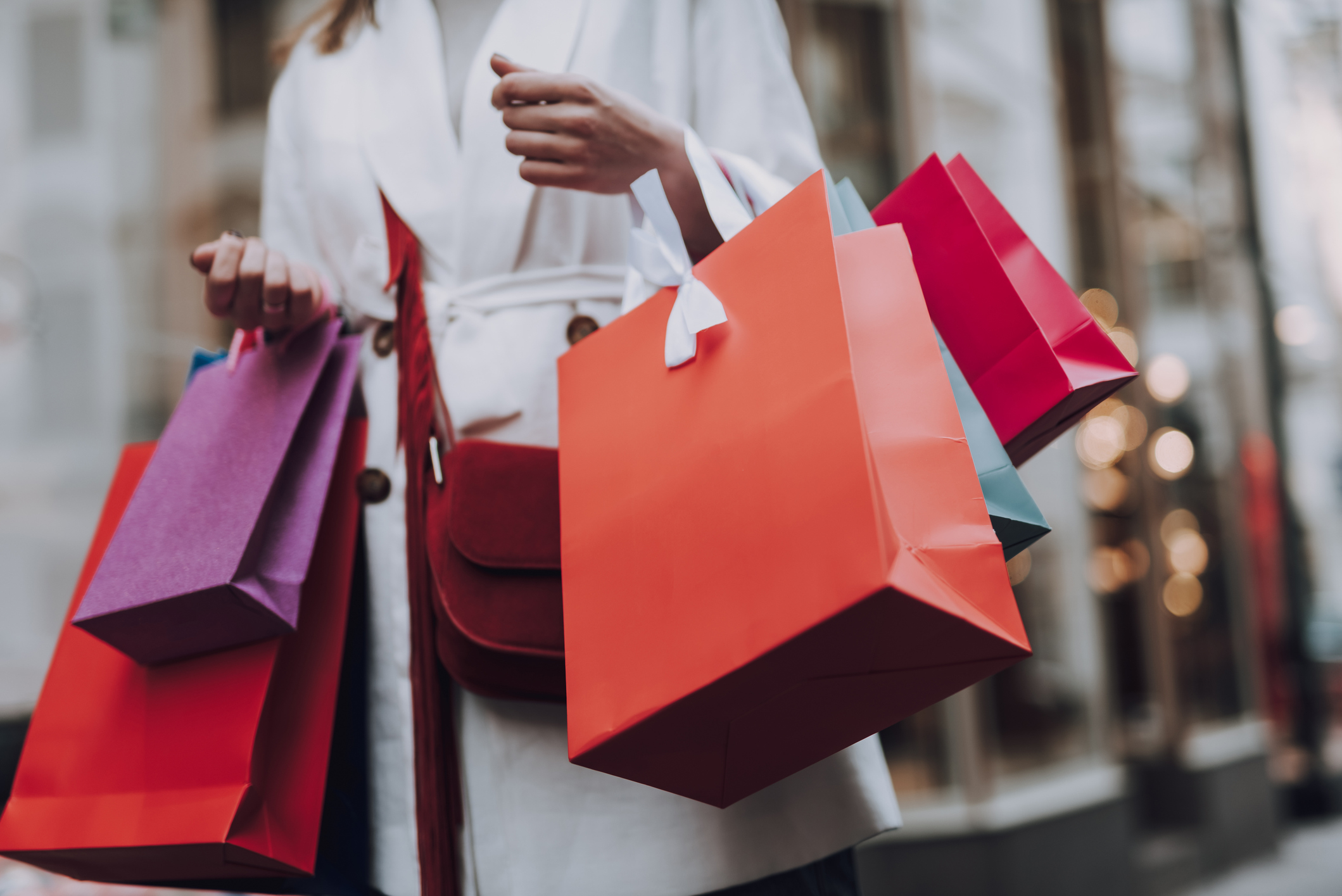 A person holding multiple colorful shopping bags while walking on a city street