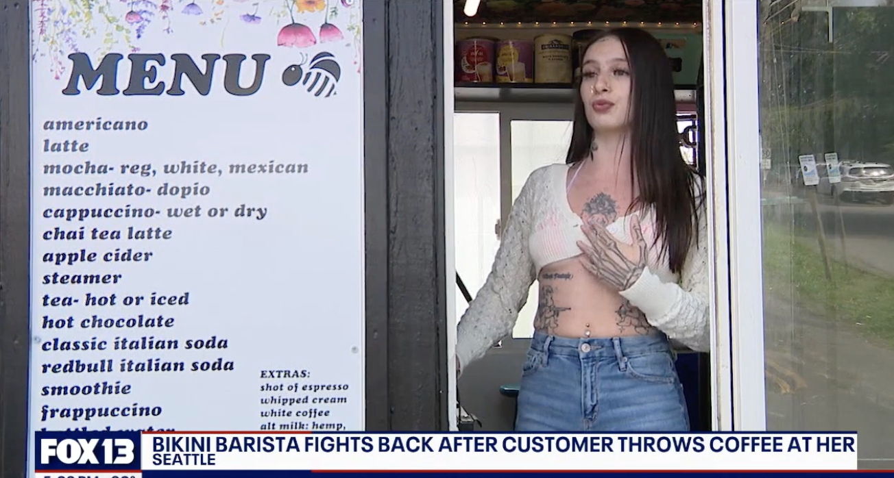 A barista in crop top and jeans stands next to a coffee shop menu. Headline reads, &quot;Bikini barista fights back after customer throws coffee at her - Seattle.&quot;