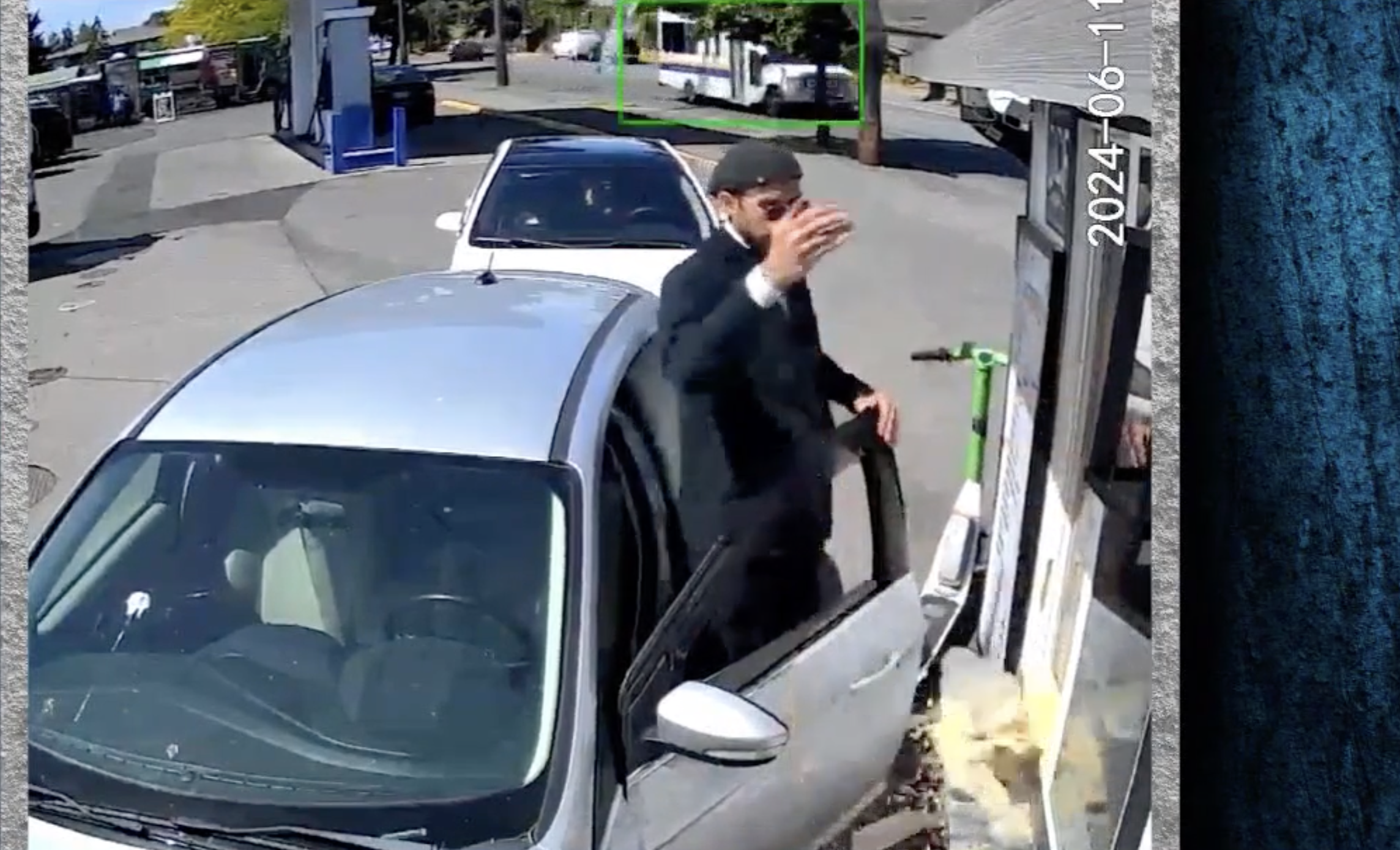 Man in a dark hat and jacket exits a silver car in a parking lot. Surveillance timestamp shows &quot;2023-06-11.&quot; Scene captured on a clear day