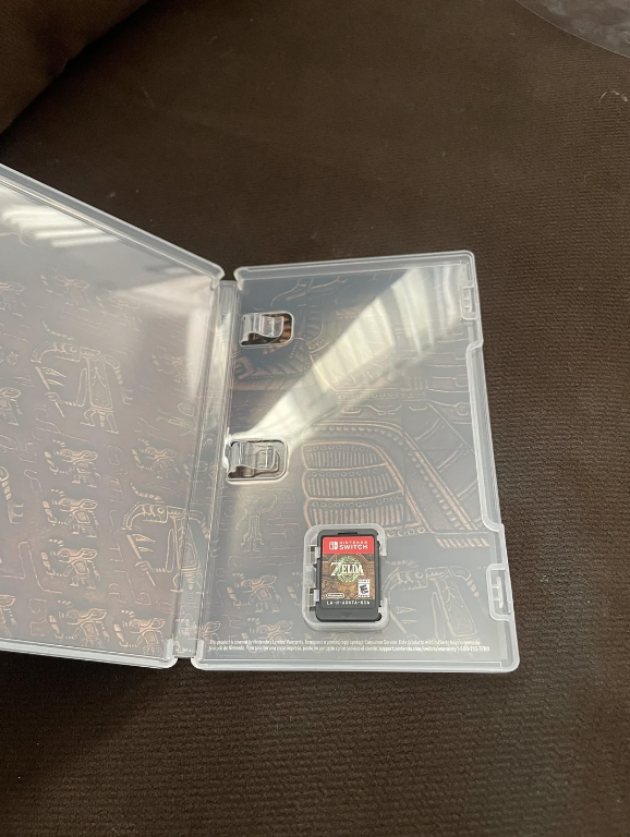The image shows a clear plastic Nintendo Switch game case opened, with a single game cartridge for &quot;The Legend of Zelda: Tears of the Kingdom&quot; inside
