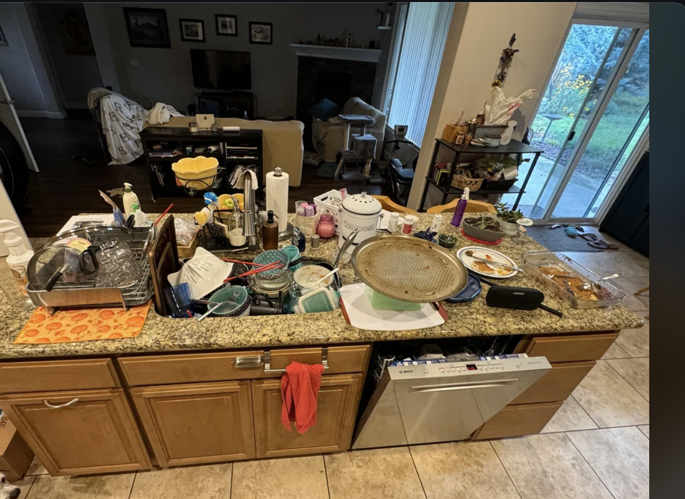 A cluttered kitchen counter with dishes, food containers, and various items spread out.