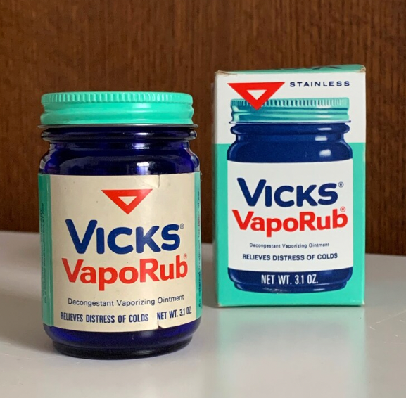 A jar of Vicks VapoRub and its box, showing the label &quot;Decongestant Vaporizing Ointment. Relieves distress of colds. Net Wt. 3.1 oz.&quot;