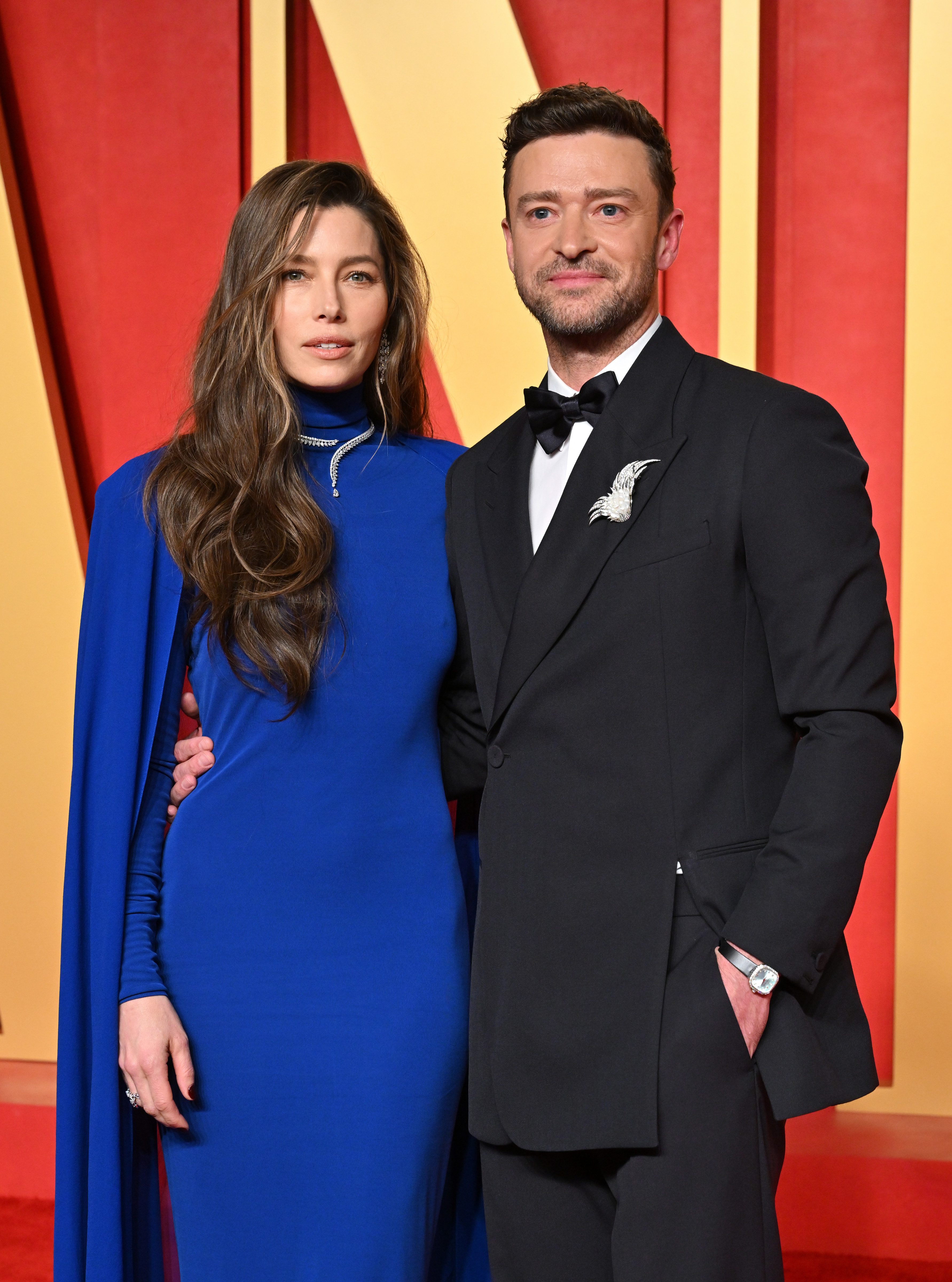 Jessica Biel wearing a long, flowing blue dress and Justin Timberlake in a black tuxedo, posing together on a red carpet