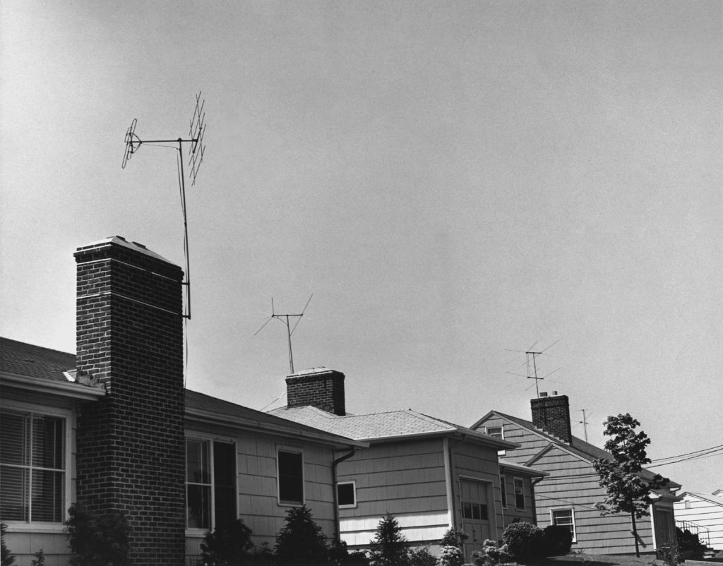 Rooftops of mid-century suburban homes with TV antennas; article categorized as Rewind