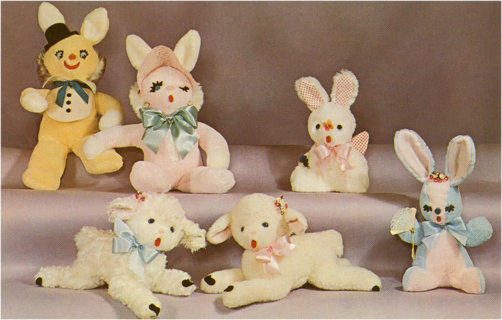 Six plush toys including bunnies and lambs, each adorned with ribbons and detailed facial features, arranged in a display
