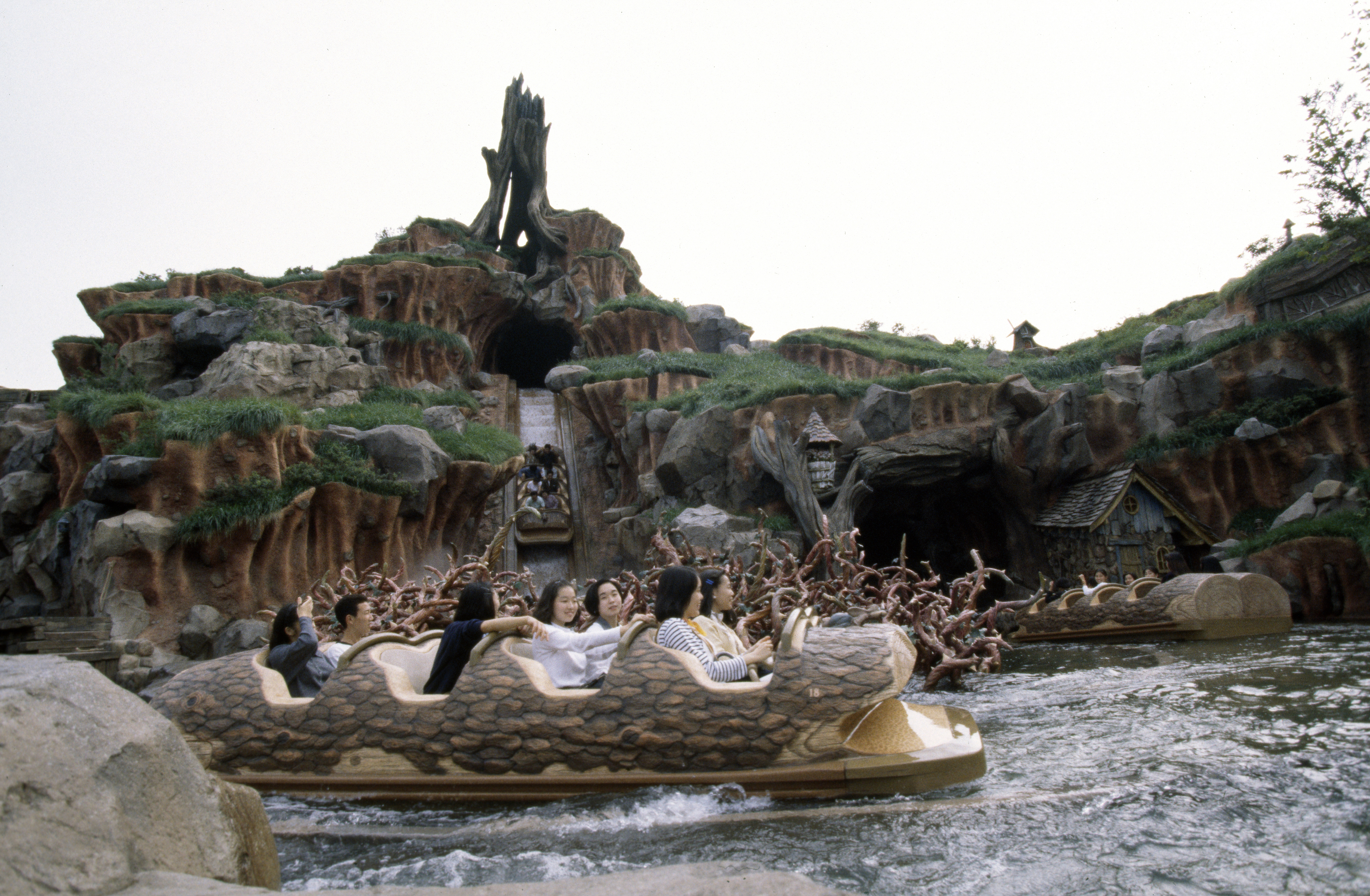People riding log boats at Splash Mountain, an outdoor amusement park water ride with animated characters and steep drops