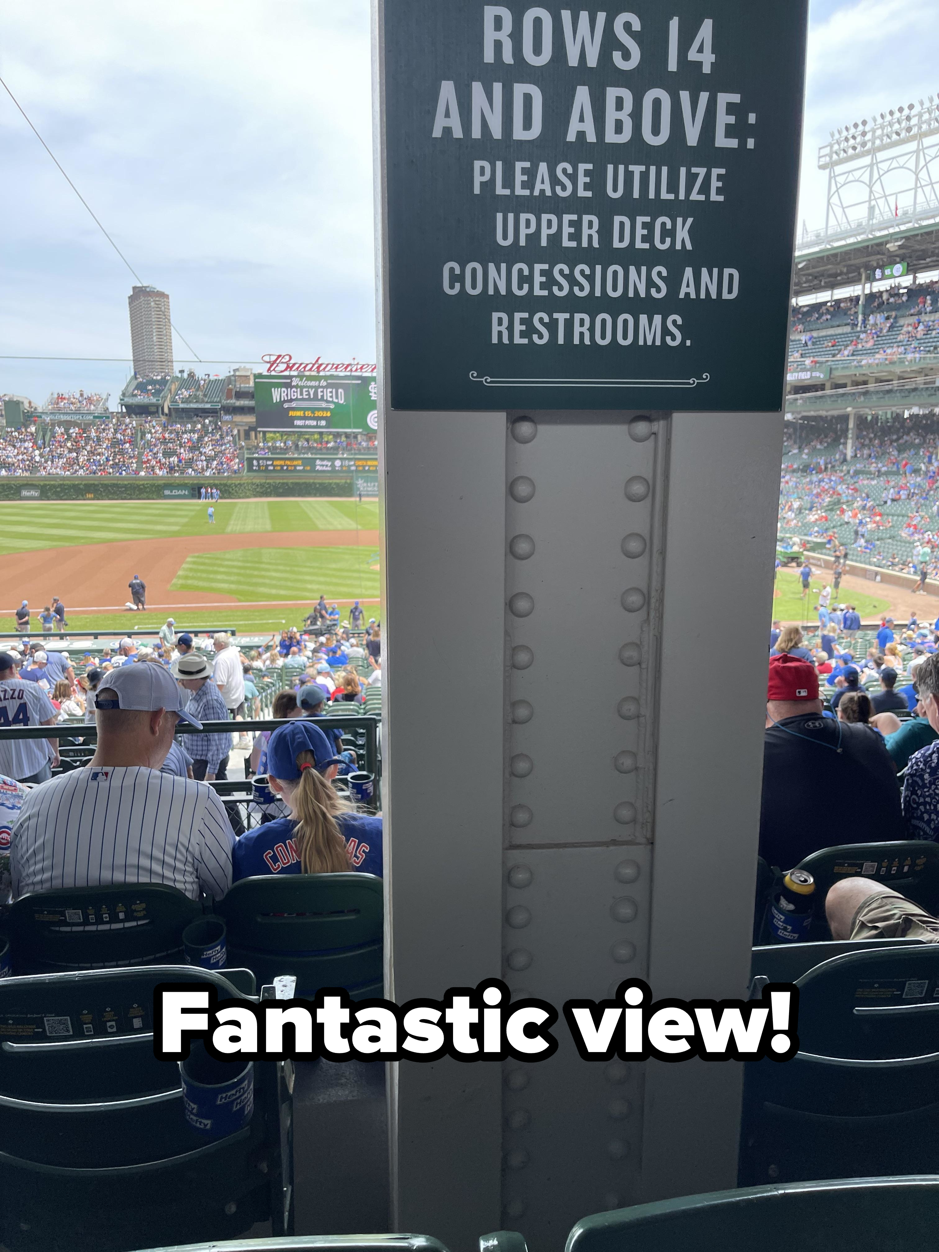 A sign at a baseball game says, &quot;Rows 14 and above: Please utilize upper deck concessions and restrooms.&quot; Fans are seated in the stadium, and the game is ongoing