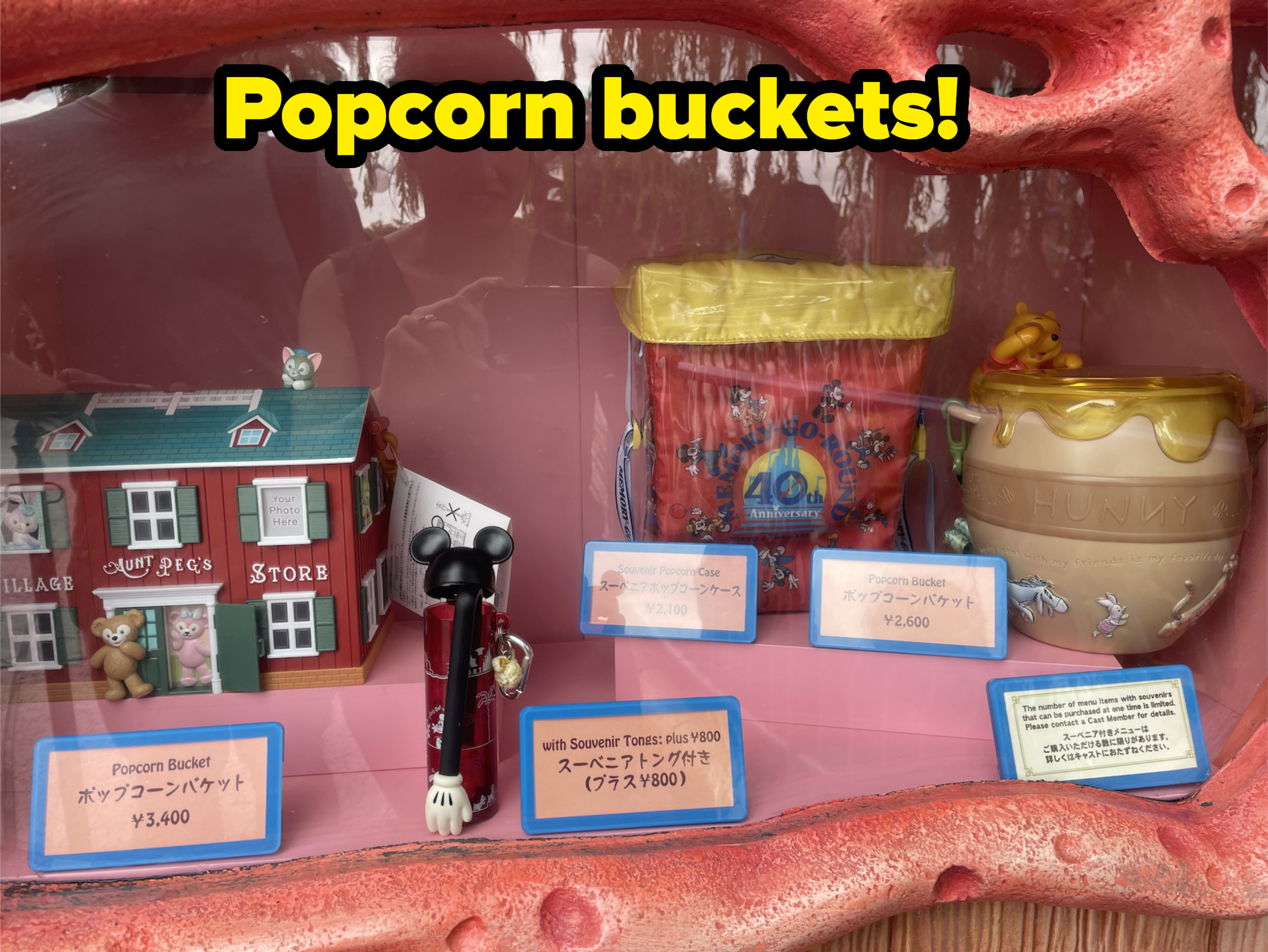 Display window showcasing Disney-themed popcorn buckets and souvenir items, including a Mickey-themed pen, a toy store, and a honey pot