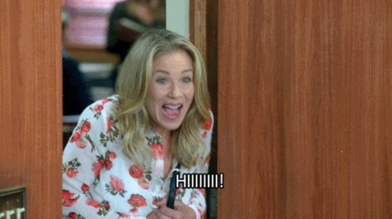 Christina Applegate excitedly peeks around a doorframe, wearing a floral-patterned top, with &quot;HIIIII!&quot; captioned at the bottom