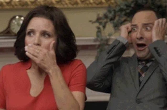 Julia Louis-Dreyfus and Tony Hale reacting in shock with hands on their faces. Julia wears a V-neck dress, and Tony is in a suit and tie