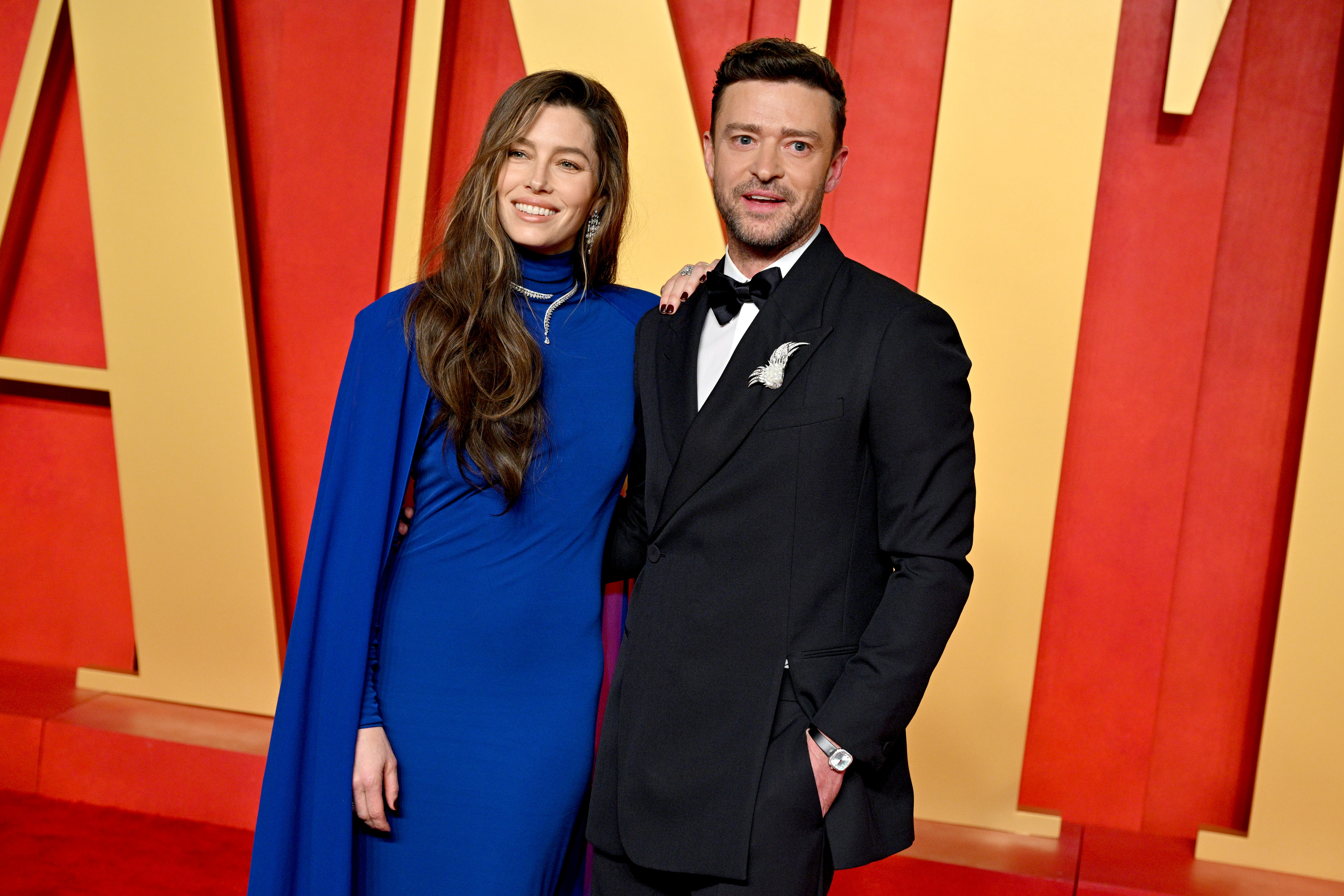 Jessica Biel in a long, elegant dress with a cape and Justin Timberlake in a black suit and bow tie pose together on the red carpet