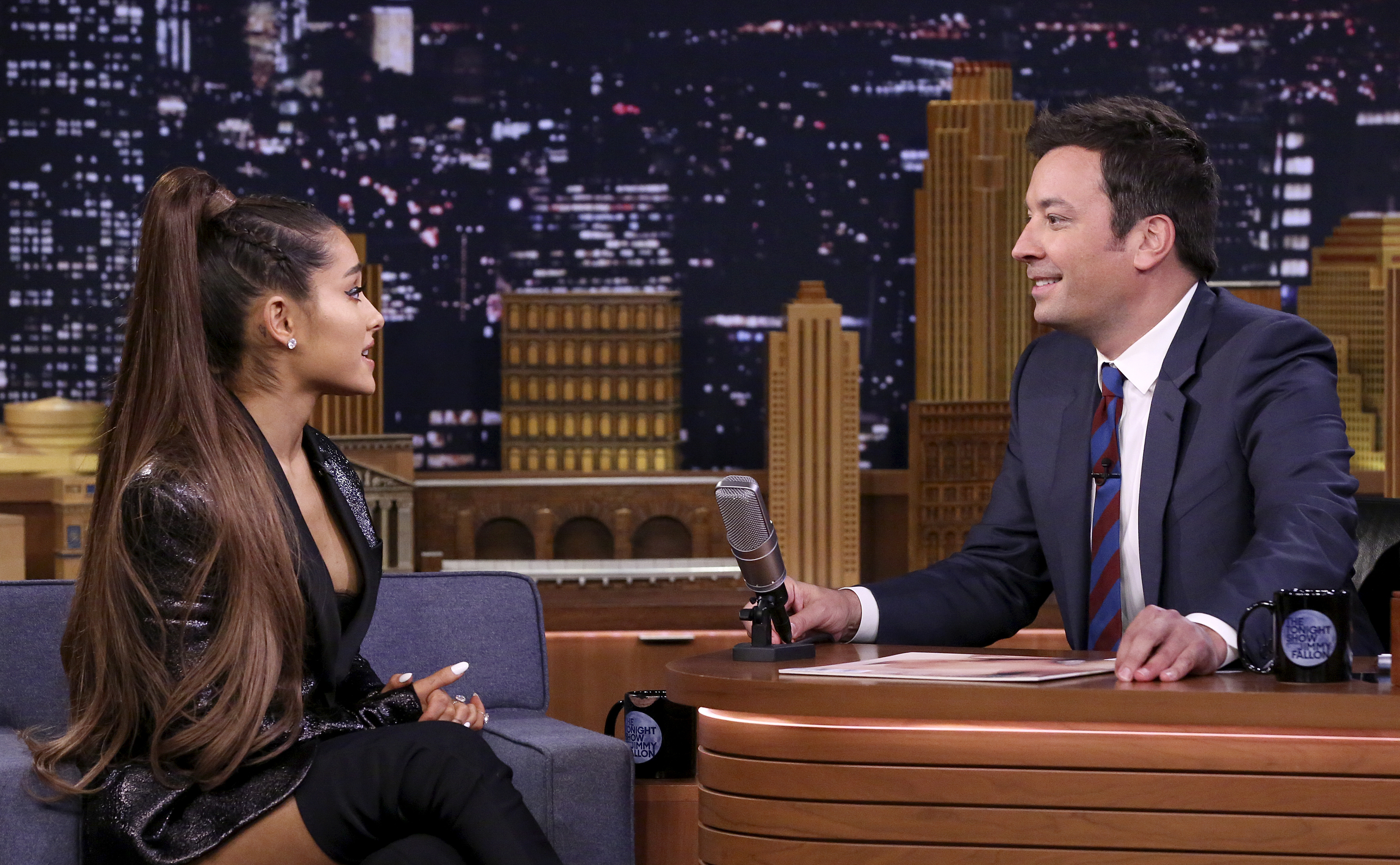 Ariana Grande, in a stylish outfit with long hair in a high ponytail, is interviewed by Jimmy Fallon on &quot;The Tonight Show&quot; set