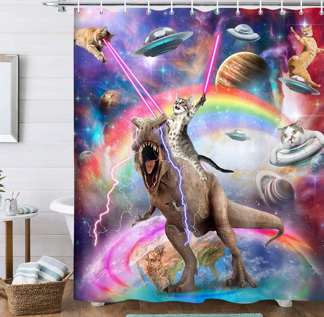 Shower curtain with a fantastic scene: cats wielding lightsabers, riding dinosaurs, and flying spaceships in a galaxy setting with planets and a rainbow