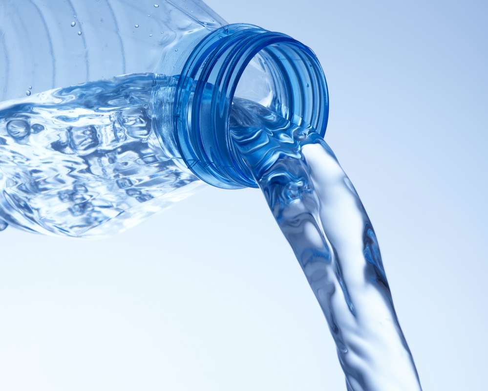 A plastic water bottle being tipped, pouring out water